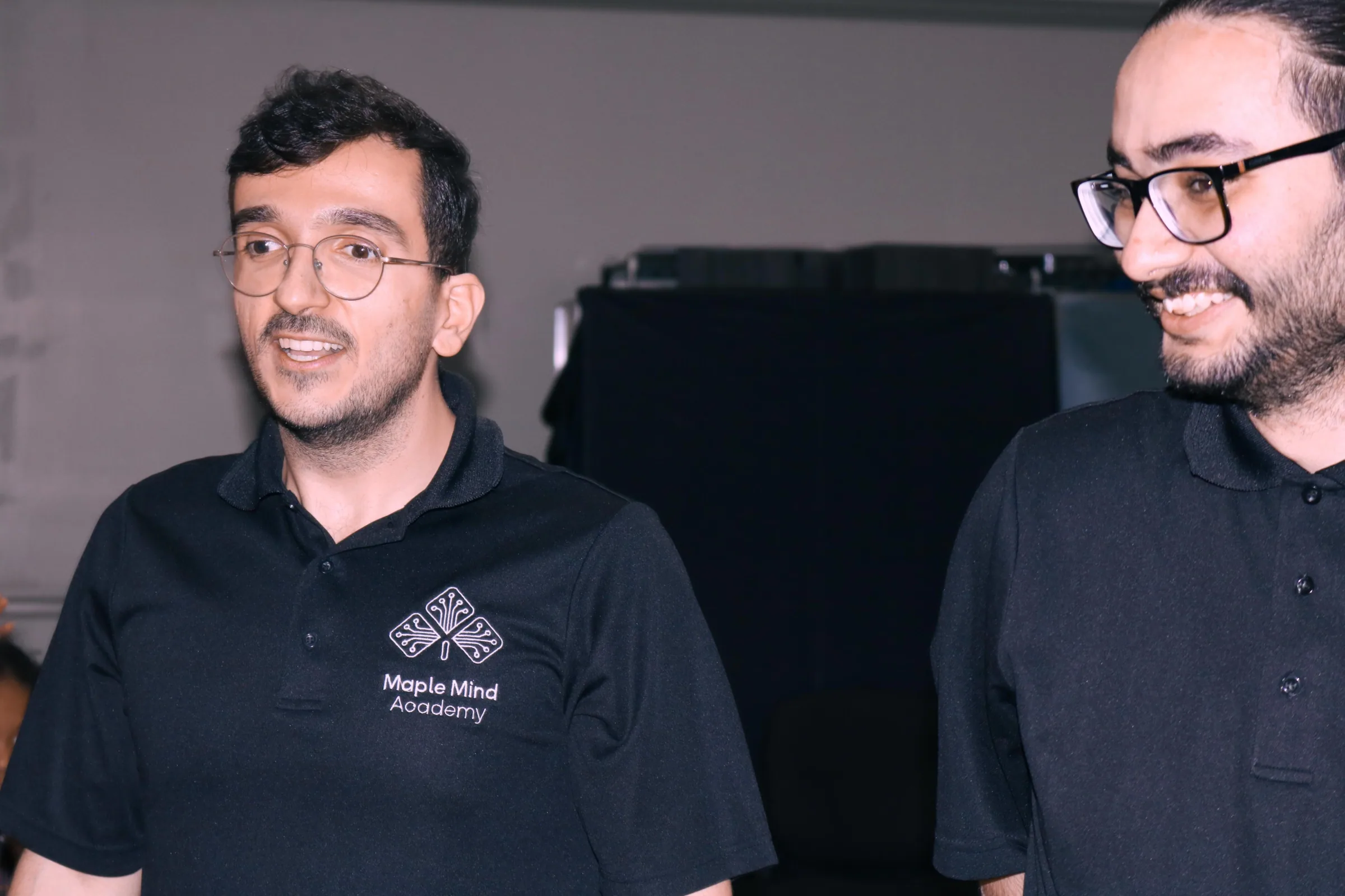 Two smiling instructors in matching black polo shirts during an event